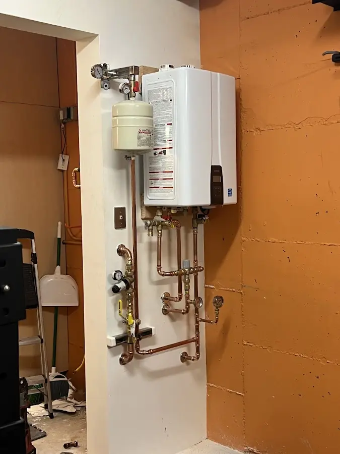 Plumbing technician inspecting water heater connections in Goshen